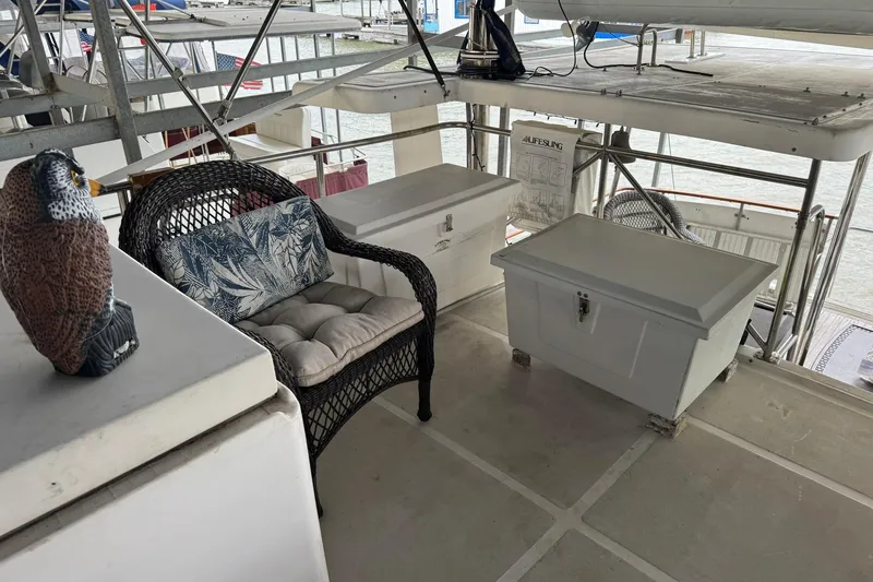Slide: The Image of 1991 DeFever 44 yacht deck with wicker chair, storage boxes, and decorative owl. - 27