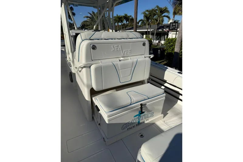 Slide: The Image of 2024 SeaVee 290B boat interior with cushioned seating, palm trees in the background. - 10