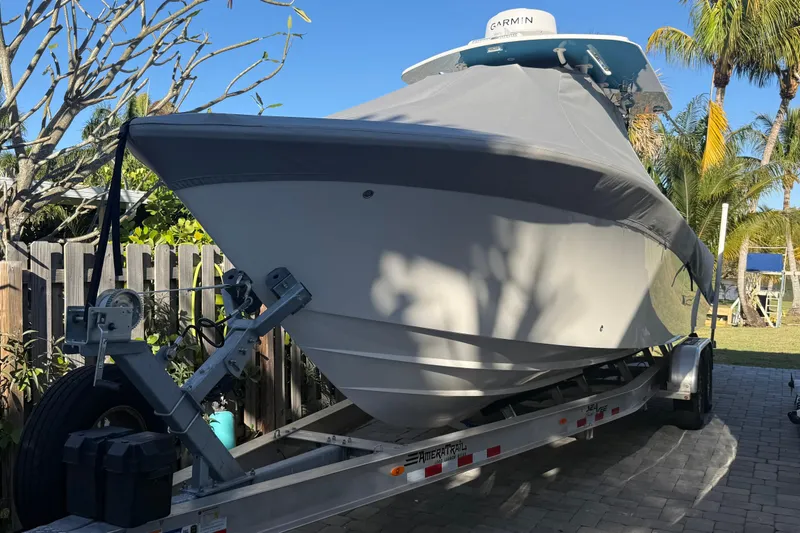 Slide: The Image of 2024 SeaVee 290B boat on trailer, covered, with Garmin equipment, surrounded by tropical trees. - 3
