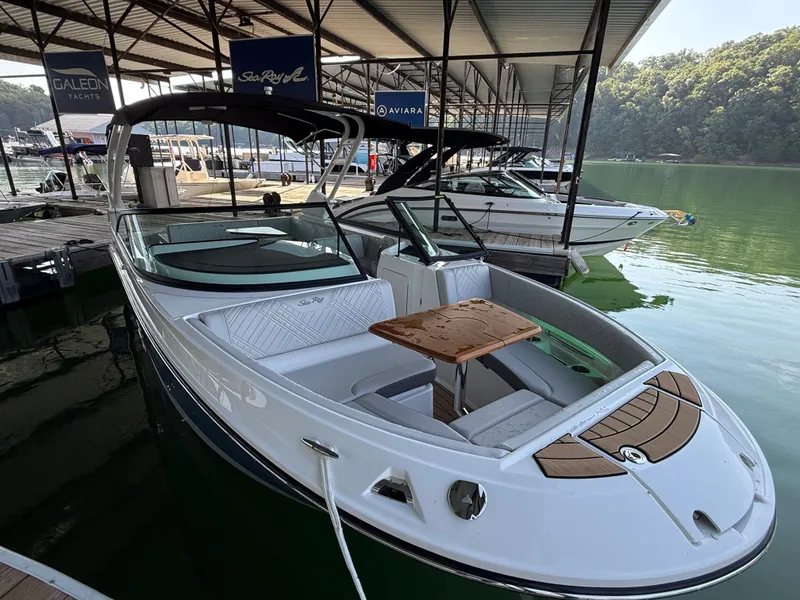 Slide: The Image of A 2026 Sea Ray SDX 250 is docked under a covered area. It features a sleek design with a wooden table in the foreground. - 2