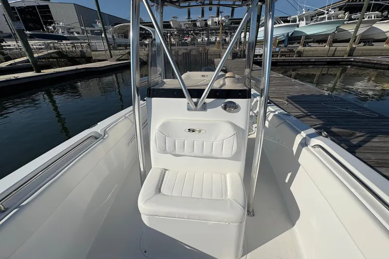 Slide: The Image of 2014 Sea Hunt Triton 225 boat interior at marina, featuring white seating and console. - 13