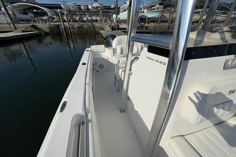 Slide: The Image of 2014 Sea Hunt Triton 225 boat docked, showcasing sleek white interior and chrome details. - 14