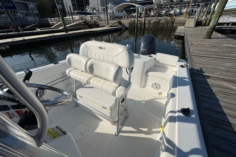 Slide: The Image of 2014 Sea Hunt Triton 225 boat interior with seating and steering wheel at dock. - 17
