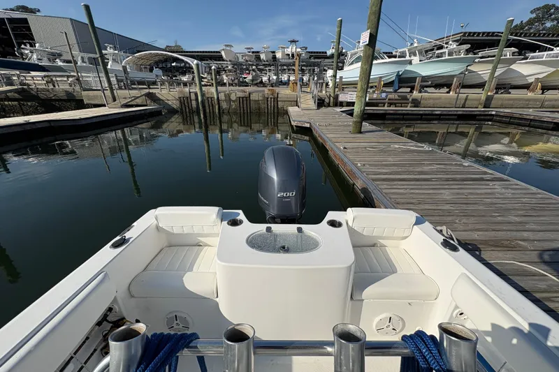 Slide: The Image of 2014 Sea Hunt Triton 225 boat docked at marina with outboard motor. - 26