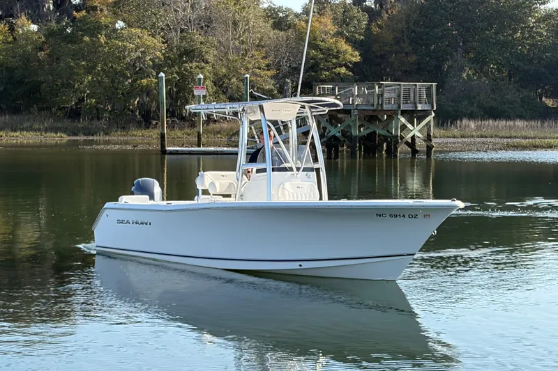Slide: The Image of 2014 Sea Hunt Triton 225 boat on calm water near a wooden dock. - 27