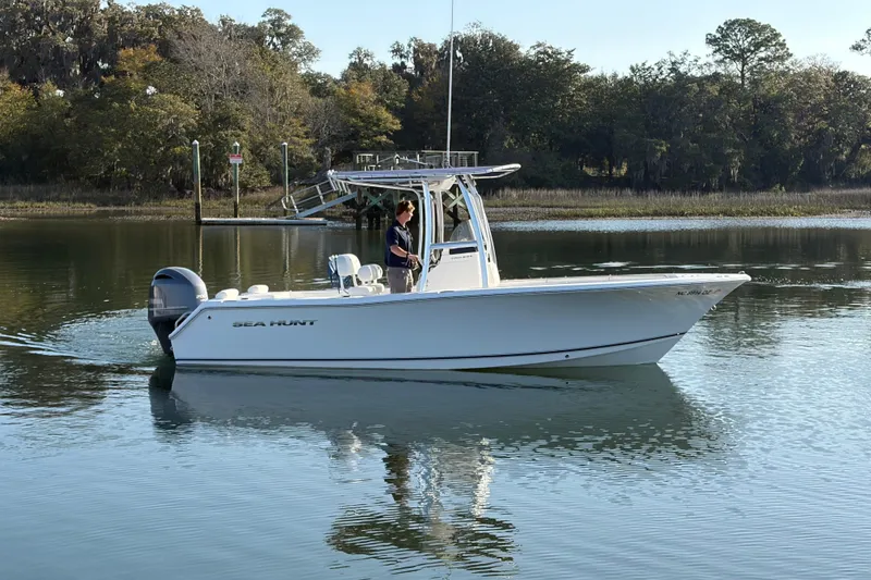 Slide: The Image of 2014 Sea Hunt Triton 225 boat on calm water, surrounded by trees. - 28