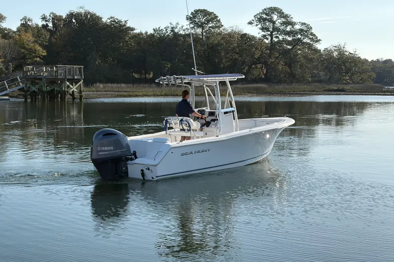 Slide: The Image of 2014 Sea Hunt Triton 225 boat cruising on calm water near a wooden dock. - 30