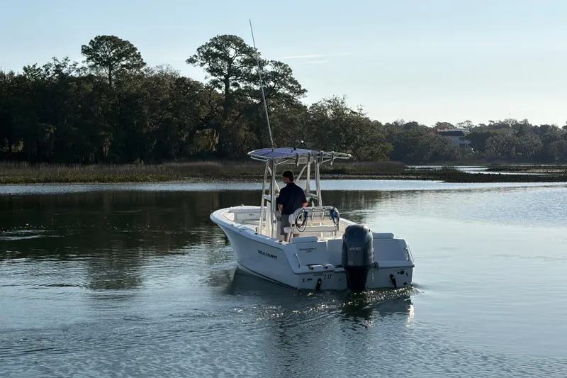 Slide: The Image of 2014 Sea Hunt Triton 225 boat cruising on a calm river with trees in the background. - 31