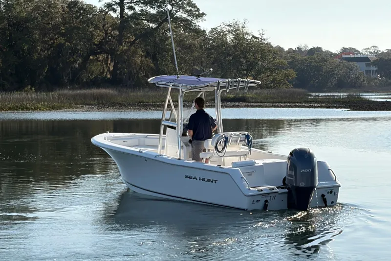 Slide: The Image of 2014 Sea Hunt Triton 225 boat cruising on a calm river with lush greenery. - 32