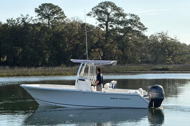 Slide: The Image of 2014 Sea Hunt Triton 225 boat on calm water, surrounded by trees. - 34