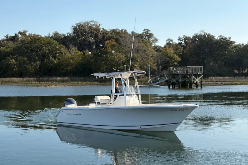 Slide: The Image of 2014 Sea Hunt Triton 225 boat on calm water near a wooden dock. - 35