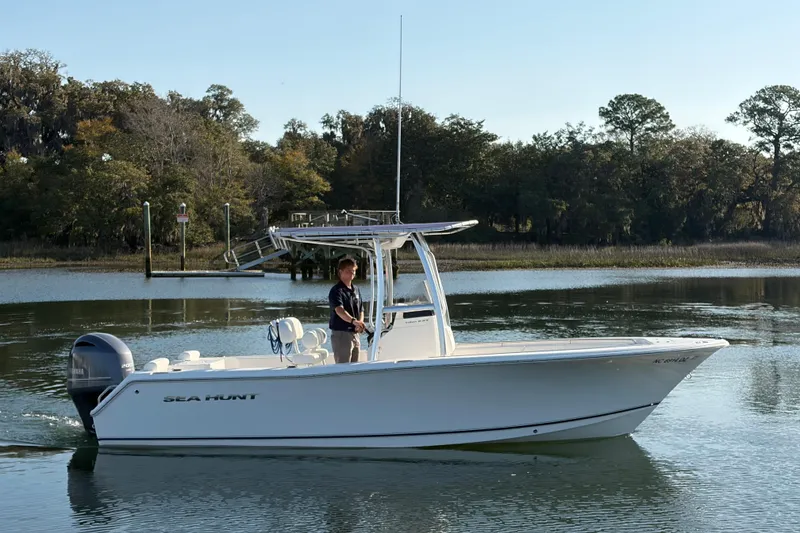 Slide: The Image of 2014 Sea Hunt Triton 225 boat on calm water with trees in the background. - 36