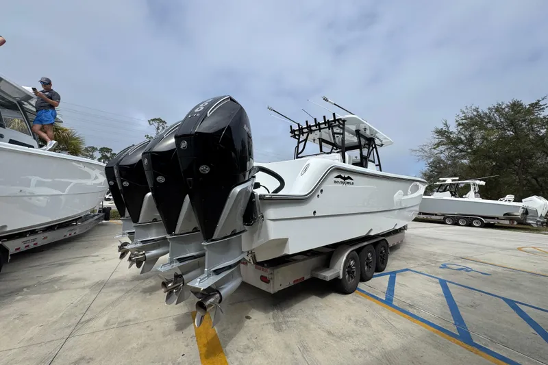 Slide: The Image of 2026 Invincible 36 Catamaran with triple outboard engines on a trailer in a marina. - 12