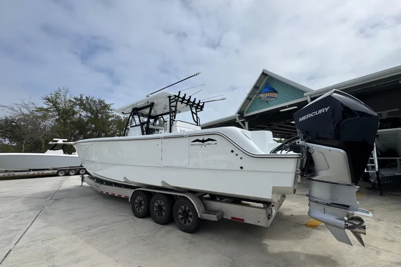 Slide: The Image of 2026 Invincible 36 Catamaran with Mercury engine on trailer, parked outdoors. - 16
