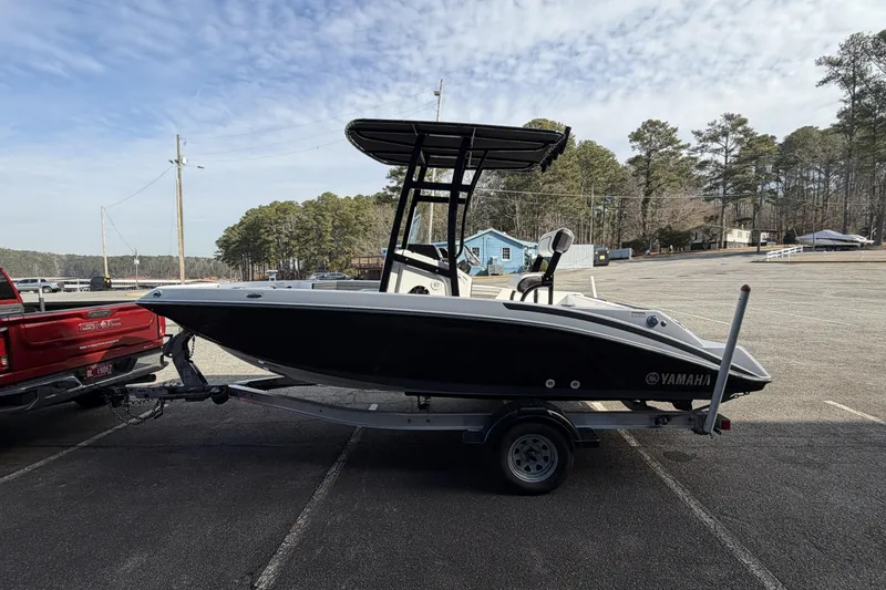 Slide: The Image of 2021 Yamaha Boats 195 FSH Sport on trailer, parked outdoors near trees and buildings. - 6