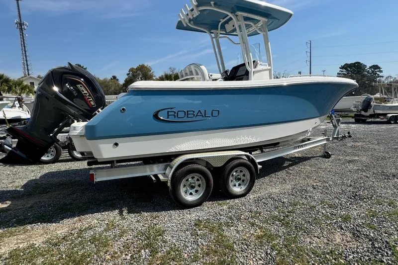 Slide: The Image of 2026 Robalo R232 Explorer boat on trailer, blue and white design, parked outdoors. - 2