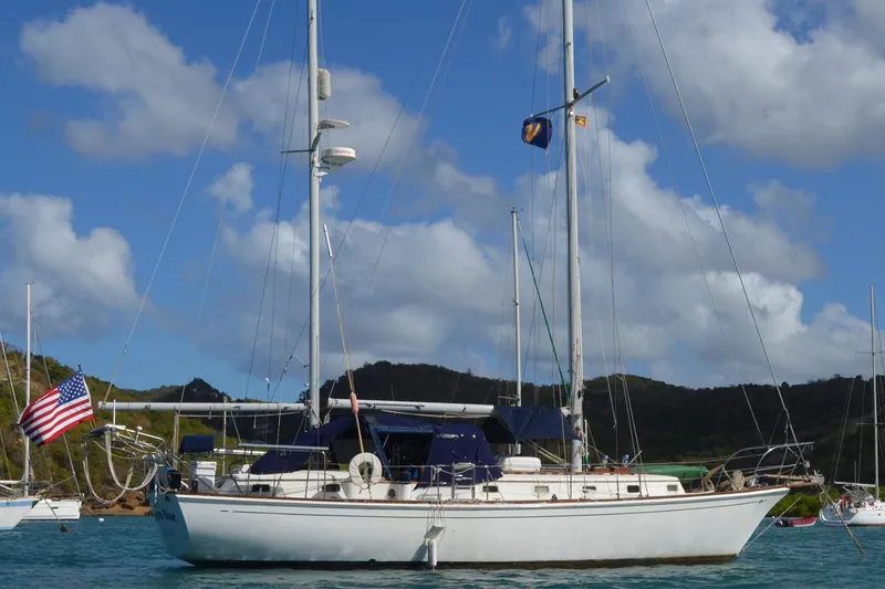 The Image of 1980 Dickerson Center Cockpit Ketch sailboat anchored in scenic bay with American flag. - 0