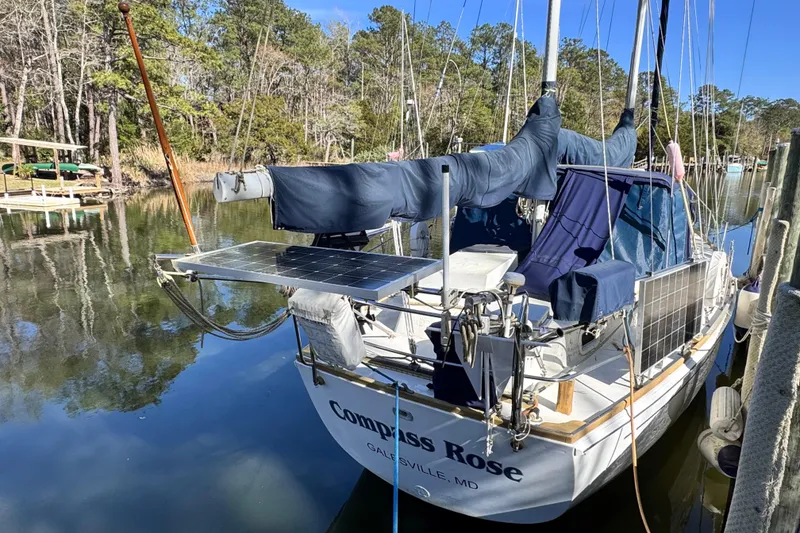 Slide: The Image of 1980 Dickerson Center Cockpit Ketch sailboat docked, featuring solar panels and blue covers. - 2
