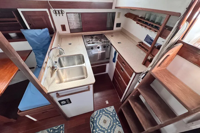 Slide: The Image of Interior of 1980 Dickerson Center Cockpit Ketch, featuring a compact kitchen with sink and stove. - 35