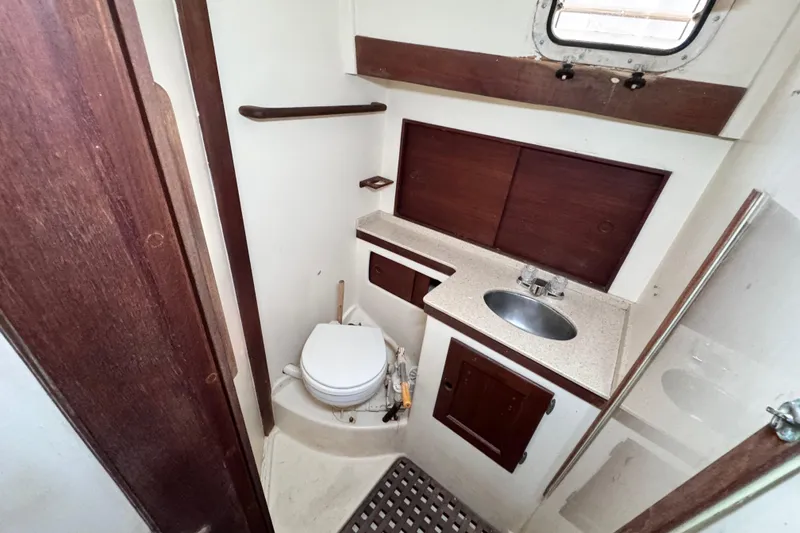 Slide: The Image of 1980 Dickerson Center Cockpit Ketch bathroom with sink, toilet, and wooden cabinetry. - 63