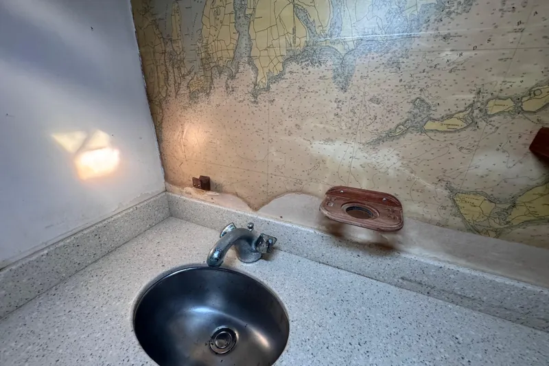 Slide: The Image of Vintage 1980 Dickerson Center Cockpit Ketch bathroom with nautical map wallpaper and stainless steel sink. - 91