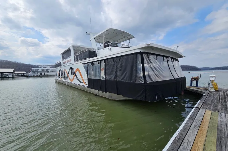 The Image of Houseboat docked on a lake, Sharpe 18x85 model, 2002, with cloudy sky backdrop. - 0