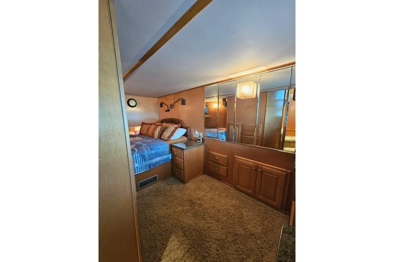 Slide: The Image of Cozy bedroom interior in 2002 Sharpe 18x85 houseboat with wood paneling and mirrored cabinets. - 36