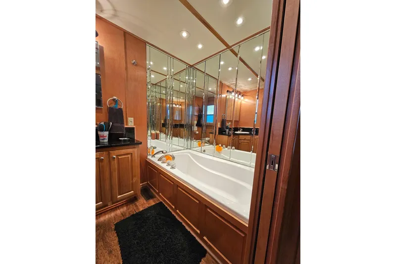 Slide: The Image of Luxurious bathroom with mirrored walls, wooden cabinets, and a large bathtub in a 2002 Sharpe 18x85. - 54