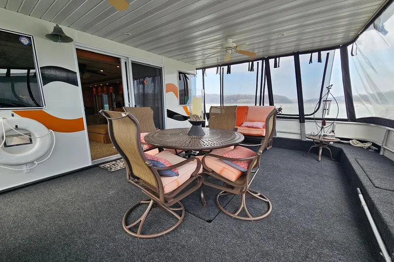 Slide: The Image of Houseboat deck with seating area, featuring a round table and chairs, Sharpe 18x85, 2002 model. - 6