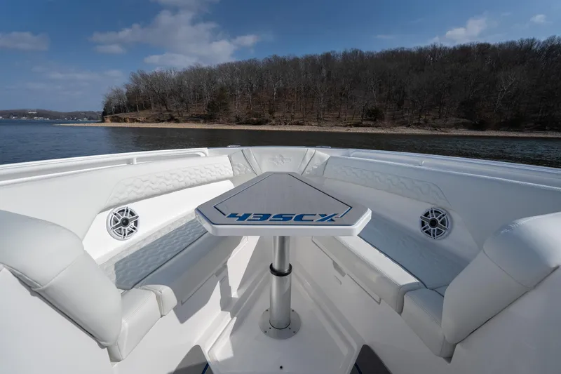 Slide: The Image of 2026 Fountain 43 SCX boat interior with white seating and table on a lake. - 12