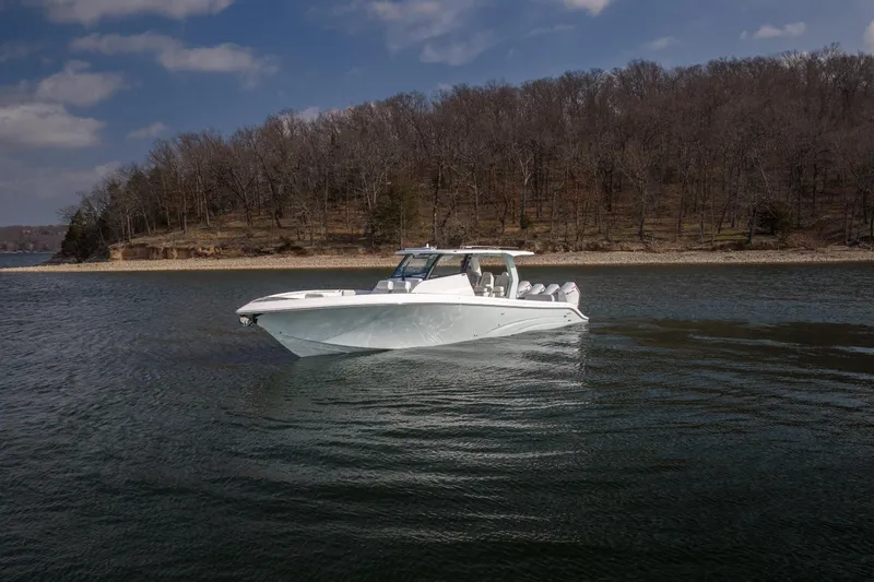 Slide: The Image of 2026 Fountain 43 SCX boat cruising on a calm lake with wooded shoreline. - 58