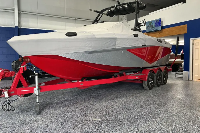 Slide: The Image of 2022 Axis T250 boat with red hull on a triple-axle trailer in showroom. - 22