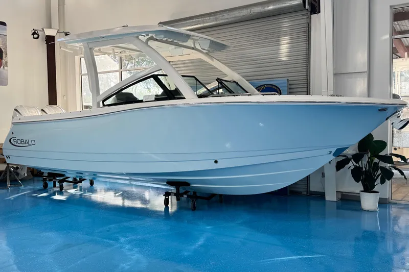 The Image of 2026 Robalo R277 Dual Console boat displayed indoors on a blue floor. - 0