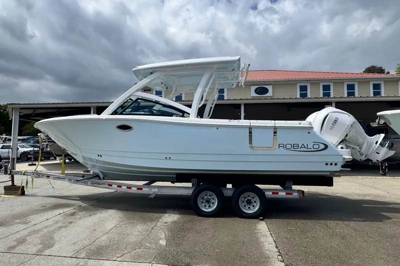 Slide: The Image of 2026 Robalo R277 Dual Console boat on trailer, parked outdoors. - 1