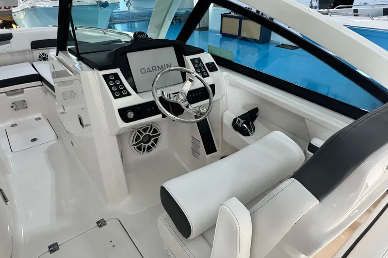 Slide: The Image of 2026 Robalo R277 Dual Console boat interior with Garmin navigation system and sleek white seating. - 2