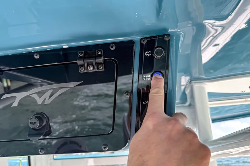 Slide: The Image of Close-up of a hand pressing a button on a 2026 Tidewater 232 LXF boat control panel. - 31