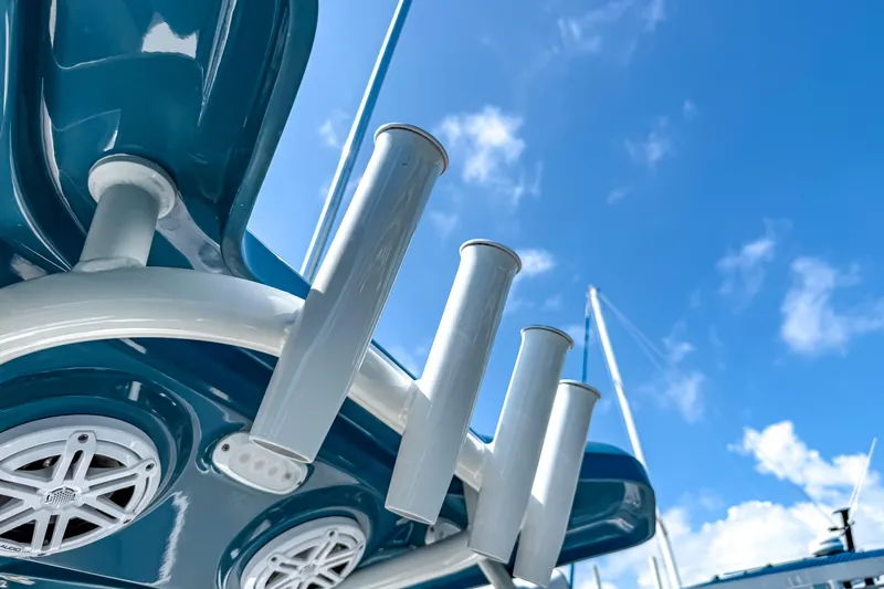 Slide: The Image of 2026 Tidewater 232 LXF boat detail with rod holders and speakers against blue sky. - 35