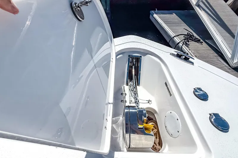 Slide: The Image of 2026 Tidewater 232 LXF boat anchor compartment with chain and winch, dockside view. - 45