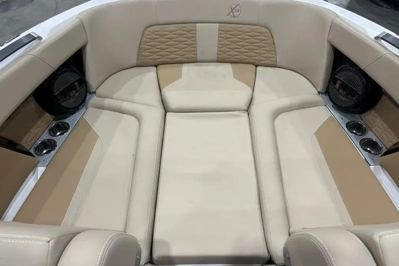 Slide: The Image of 2024 MasterCraft X24 boat interior with beige and tan seating, cup holders, and speakers. - 7