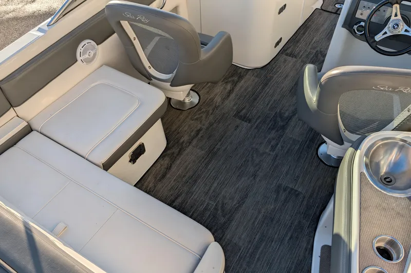 Slide: The Image of 2011 Sea Ray 240 Sundeck interior with seating, steering wheel, and sink. - 11
