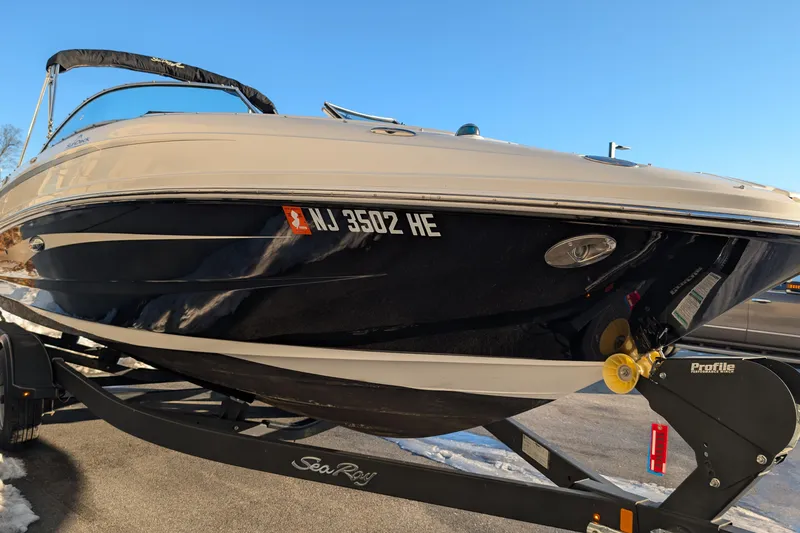 Slide: The Image of 2011 Sea Ray 240 Sundeck boat on trailer, parked outdoors under clear blue sky. - 6