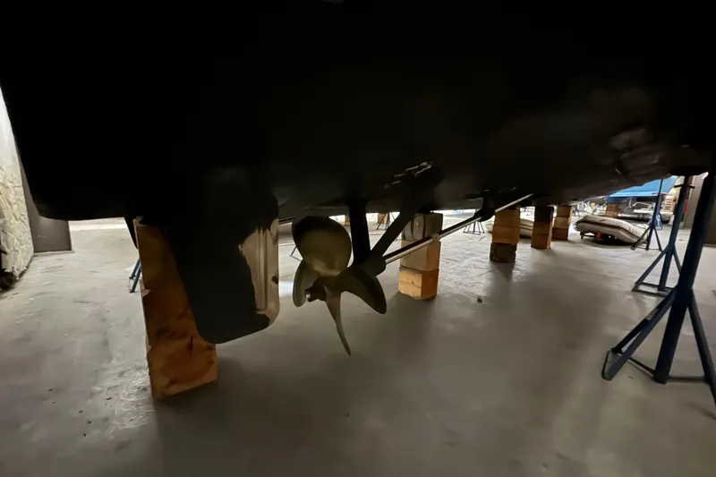 Slide: The Image of 1989 Dyna Craft 45 boat propeller and hull on supports in a workshop. - 13