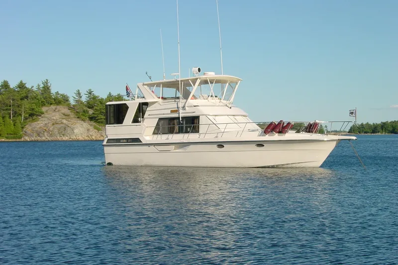 Slide: The Image of 1989 Dyna Craft 45 yacht anchored on a serene lake with forested shoreline. - 3