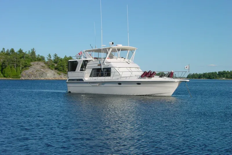 Slide: The Image of 1989 Dyna Craft 45 yacht anchored on a serene lake with forested shoreline. - 4