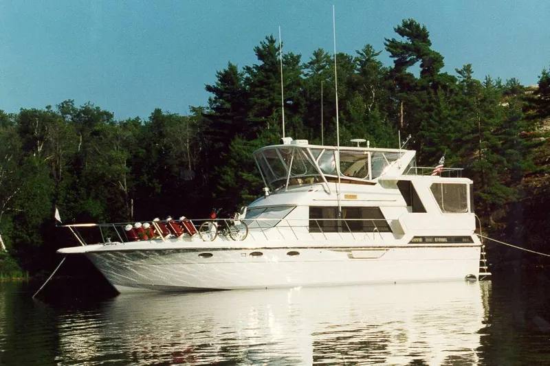 Slide: The Image of 1989 Dyna Craft 45 yacht anchored on a serene lake with lush forest backdrop. - 7