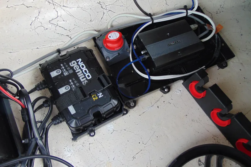 Slide: The Image of 2023 Hurricane SunDeck Sport 185 OB boat electrical components, featuring NOCO Genius charger and Kenwood amplifier. - 16