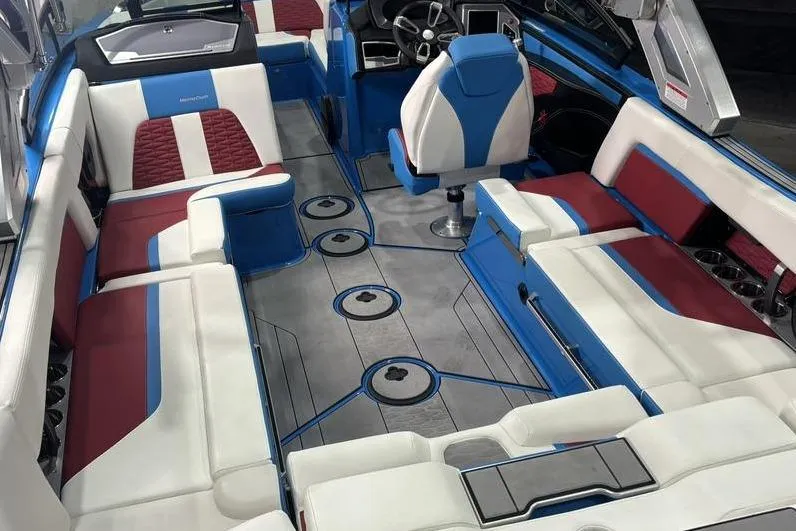 Slide: The Image of 2024 MasterCraft X24 boat interior with blue, white, and red seating, and modern dashboard. - 9