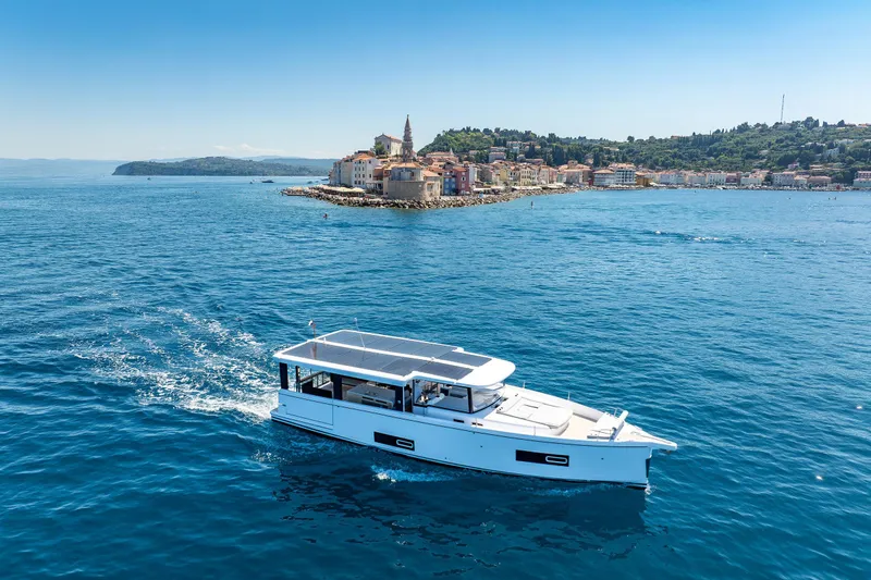 Slide: The Image of 2026 Jeanneau Sea Loft 480 cruising near a scenic coastal town. - 5