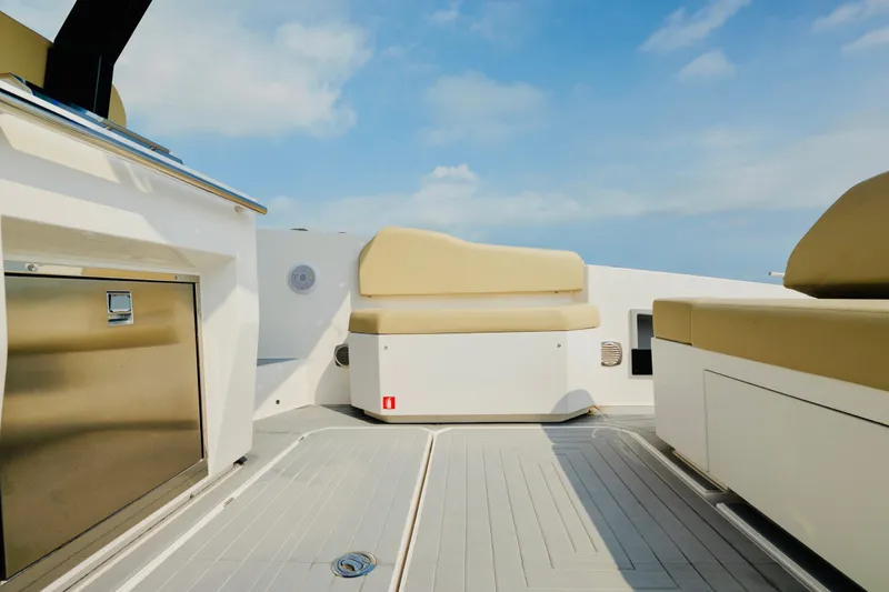 Slide: The Image of 2023 Rio Yachts Daytona 34 interior with beige seating and stainless steel accents under a clear sky. - 13