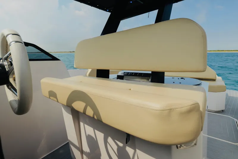 Slide: The Image of 2023 Rio Yachts Daytona 34 helm with beige seating, steering wheel, and ocean backdrop. - 20